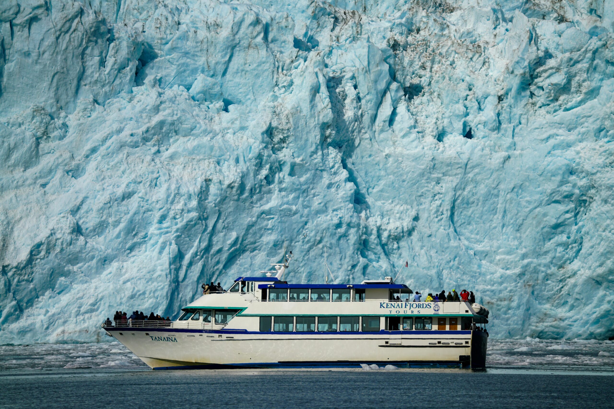 Tour boat navigating near a massive glacier, offering breathtaking views.